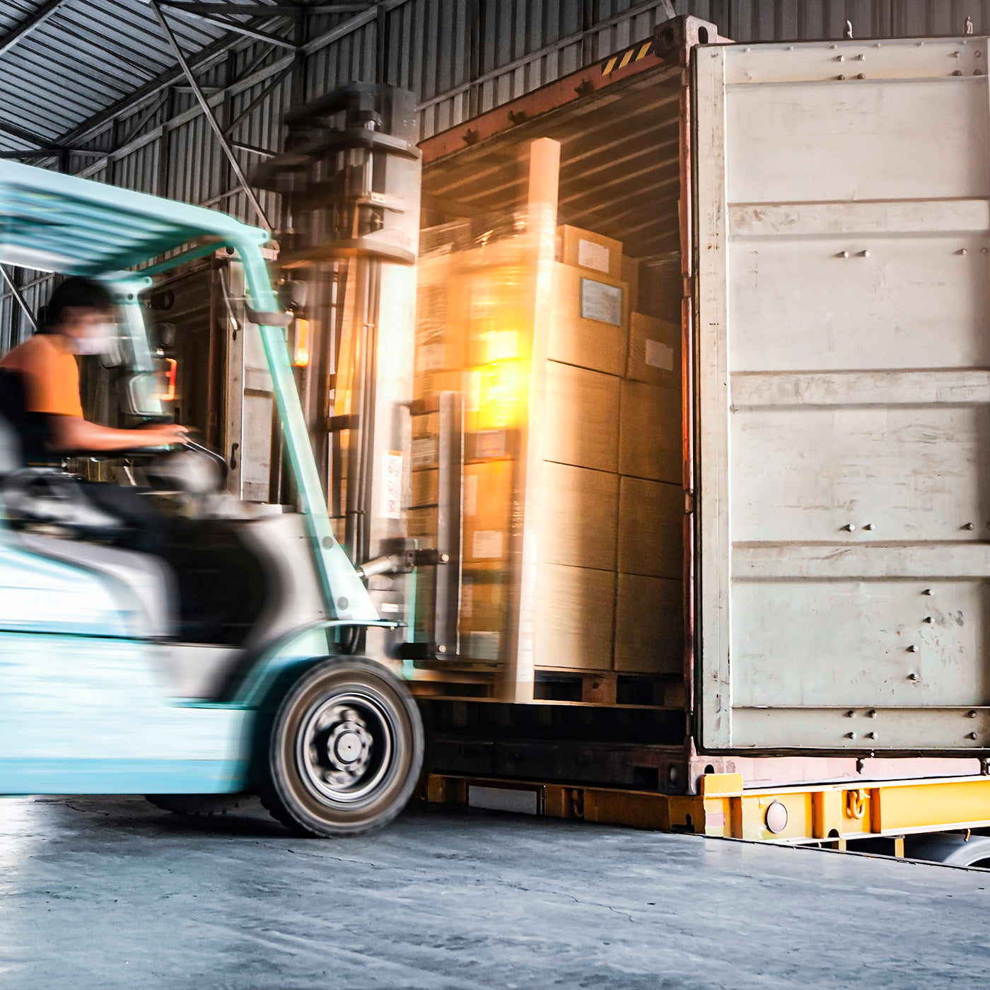 Eine Palette mit Boxen wird mit einem Gabelstapler in einen LKW geladen